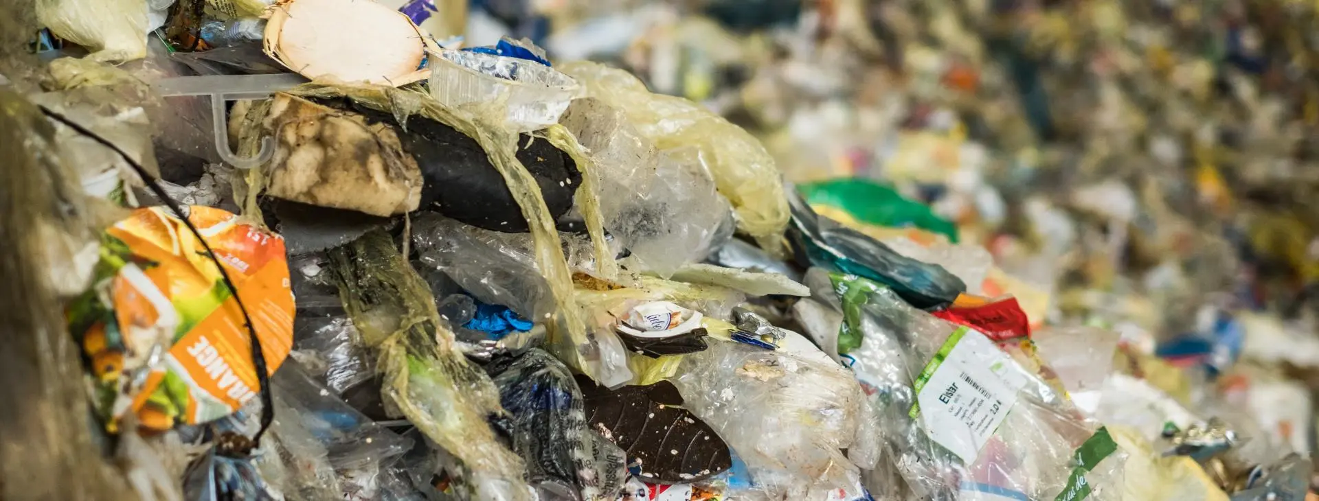 Post-consumer plastics sit in heaps in a transfer station
